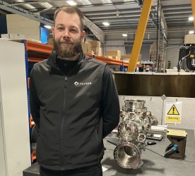 Man in black clothing standing next to vacuum chamber 